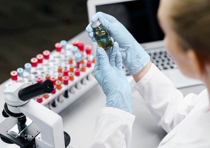 Rinite: mulher segurando frasco no laboratório.