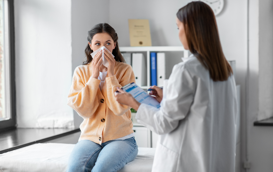 Rinite alérgica: médica conversando com paciente que está com lenço assoando nariz