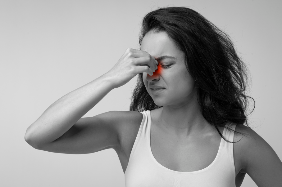 Rinite e sinusite: mulher com dor na região nasal.