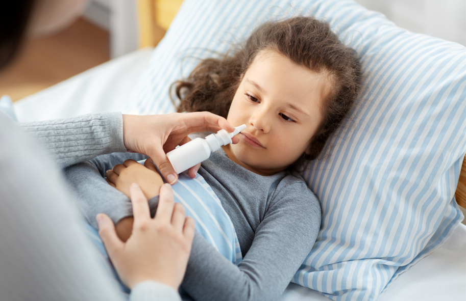 Rinite em crianças: mãe aplicando spray nasal na filha.